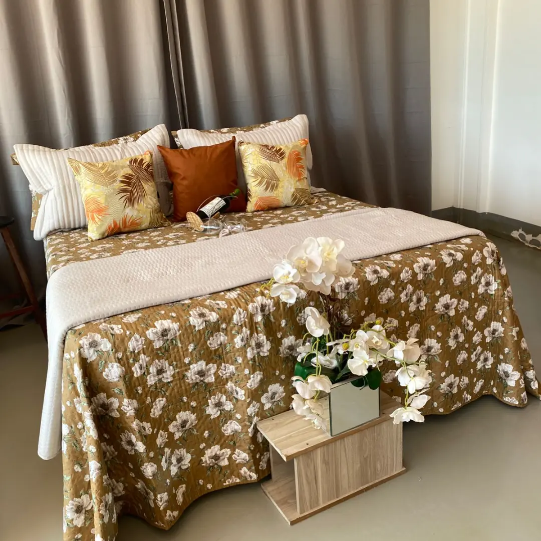 Cama posta queen com colcha matelassê floral em fundo caramelo