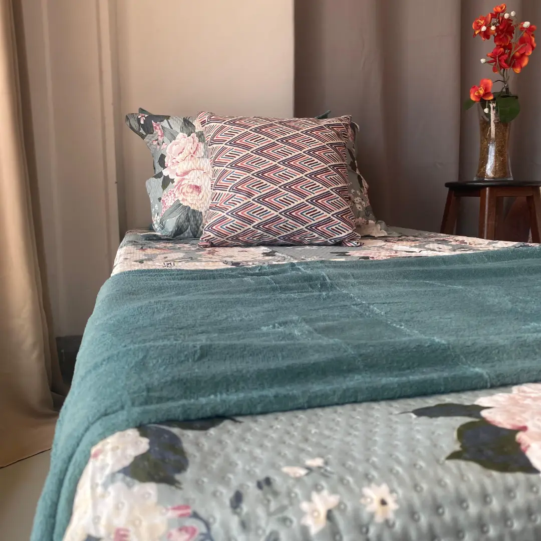 Cama com manta peluciada verde e almofadas estampadas